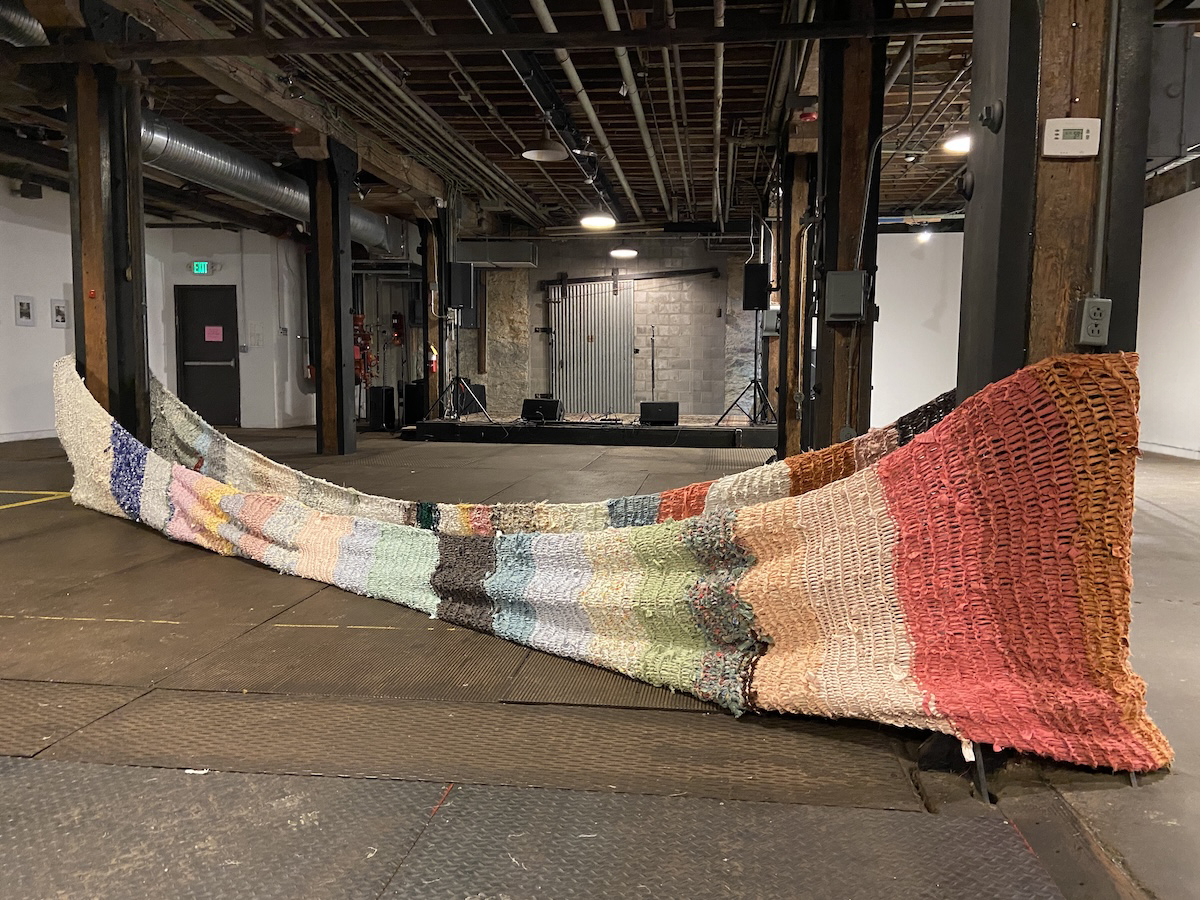 Large fabric form stretched and wrapped around two wooden pillars in an industrial space.